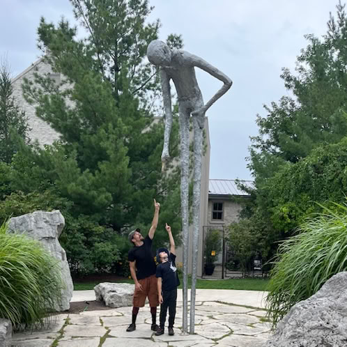 Man and boy looking up and pointing at statue pointing down