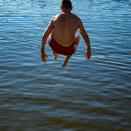 Back of man jumping into water